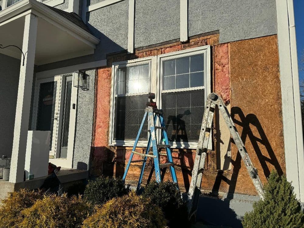 Home exterior renovation with scaffolding and insulation around windows.