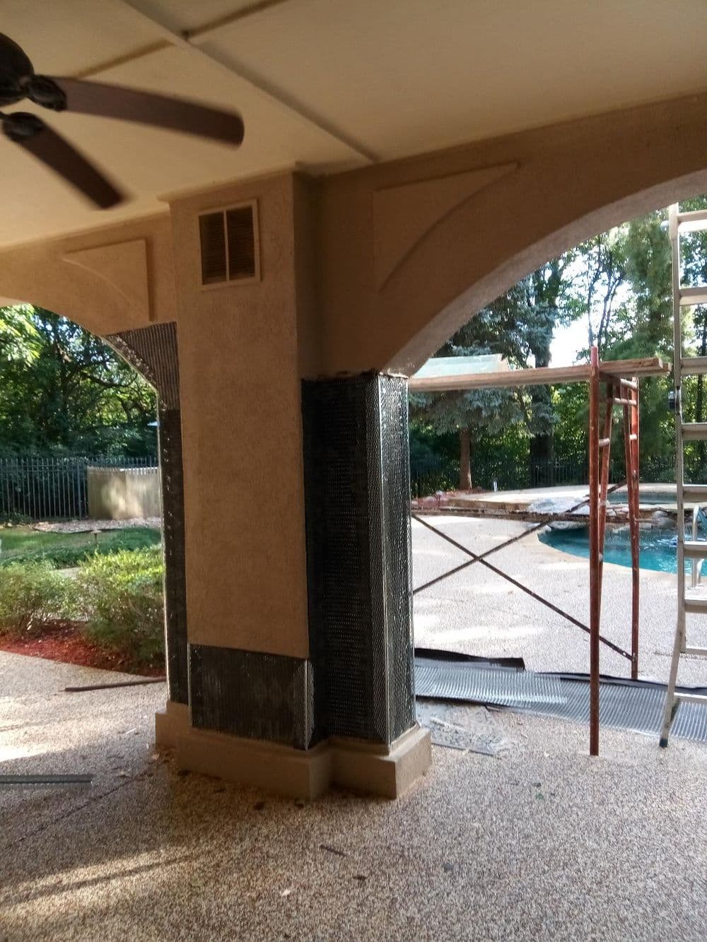 Renovation progress showing a textured column and scaffolding near a swimming pool.